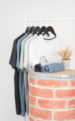 Black,blue, grey and white t-shirts on hangers on gray background