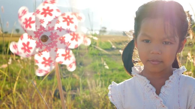 Alone girl stand in cornfield with bright pinwheel in sunbeam of a day of sun and wind. concept of leisure relaxation in vacation