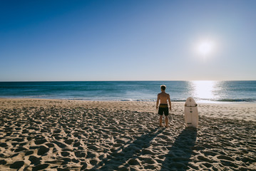 Man looking at the waves with surfboard on a beach in Portugal