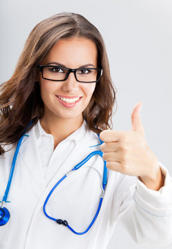 Female doctor with thumbs up gesture, over grey