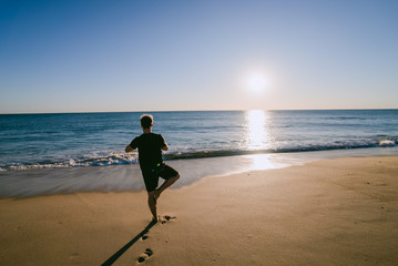 Man doing Yoga at sunset on a beach in Portugal