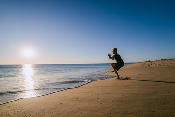 Naklejka premium Man doing Yoga at sunset on a beach in Portugal
