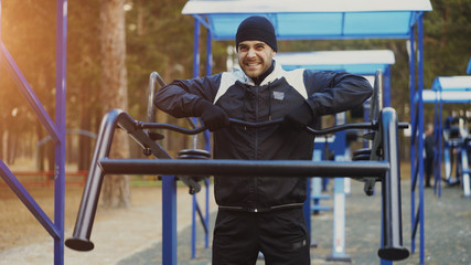 Young athlete man doing exercise at outdoor gym in winter park