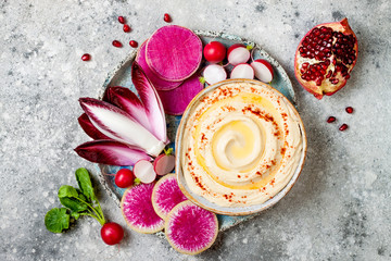 Homemade hummus seasoned with olive oil and paprika and fresh vegetables: radishes, watermelon...
