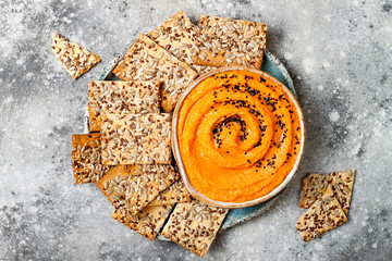 Pumpkin hummus seasoned with olive oil and black sesame seeds with whole grain crackers. Healthy...