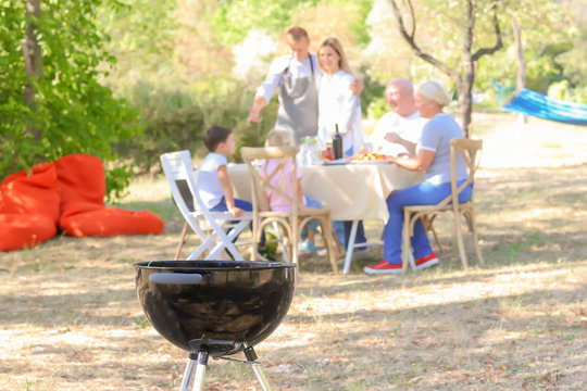 Barbecue grill and happy family on background outdoors