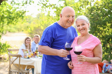 Happy senior couple with family having barbecue party outdoors