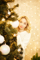 Beautiful woman with Santa hat peeking behind Christmas tree, isolated on white background