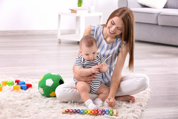 Young mother and cute baby playing on floor at home