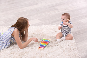 Young mother and cute baby playing on floor at home