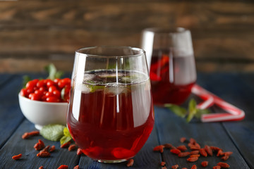 Glass with healthy goji juice on wooden table