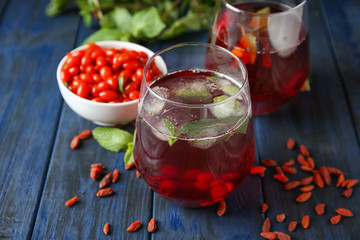 Glass with healthy goji juice on wooden table