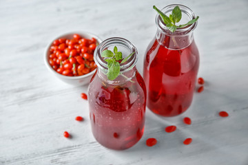 Bottles with healthy goji juice on wooden table