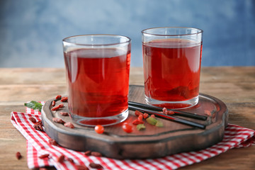 Glasses with healthy goji juice on wooden table
