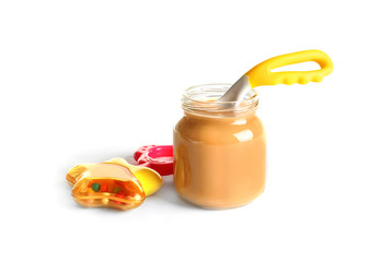 Jar with healthy baby food and rattle on white background