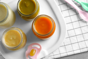 Jars with healthy baby food on table