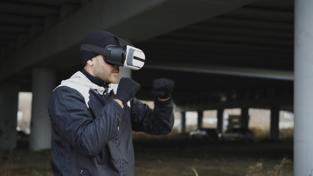 Martial boxing man in VR 360 headset training punches in virtual reality fight at urban location outdoors in winter
