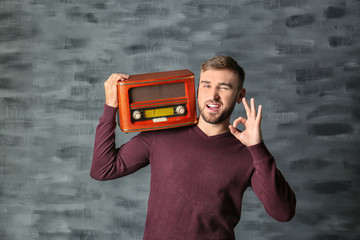 Young man listening to radio against grey background