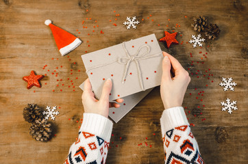 Stylish christmas flat lay with woman hands hold (open) post card letter. Holiday celebration concept woman hands in a knitted sweater writing letter. Top view.