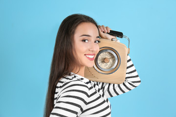 Young woman listening to radio against color background