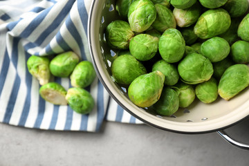 Colander with fresh raw Brussels sprouts on table