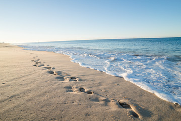 Footsteps in sand on a beach in portugal at sunrise
