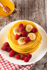 Fresh made delicious pancakes with berries, blackberries, raspberries, banana, honey and maple syrup. Healthy morning breakfast concept.