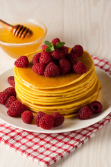 Fresh made delicious pancakes with berries, blackberries, raspberries, banana, honey and maple syrup. Healthy morning breakfast concept.