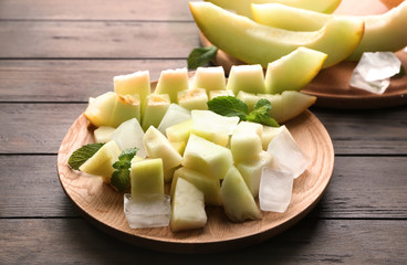 Plate with yummy melon slices on wooden table