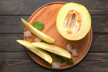 Board with yummy melon on wooden table