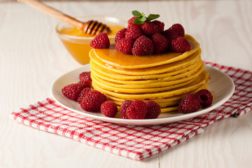 Fresh made delicious pancakes with berries, blackberries, raspberries, banana, honey and maple syrup. Healthy morning breakfast concept.