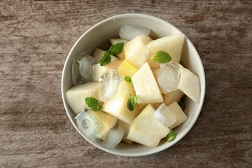 Bowl with yummy melon slices on wooden table