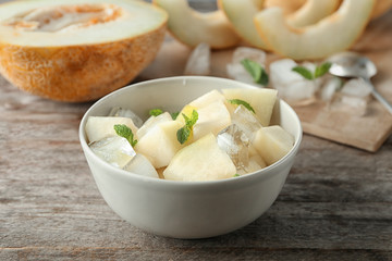 Bowl with yummy melon slices on wooden table