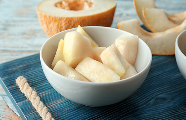 Bowl with yummy melon slices on wooden table