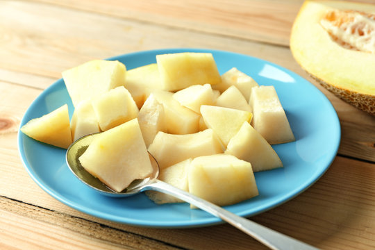 Plate with yummy melon on wooden table