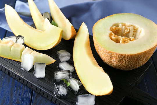Board with sliced yummy melon on wooden table