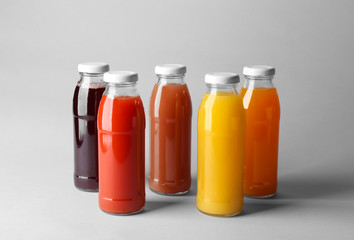 Fototapeta na wymiar Bottles with juices on light background