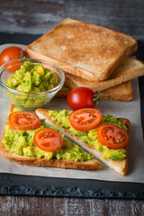 Fototapeta na wymiar Avocado toast, cherry tomato on wooden background. Breakfast with toast avocado, vegetarian food, healthy diet concept.