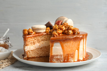 Plate with delicious caramel cake on table