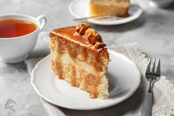 Plate with piece of delicious caramel cake on table
