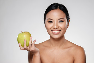Cheerful lady smiling and eating green apple isolated