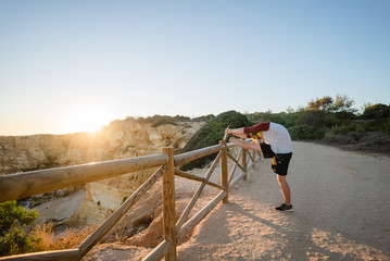 Man stretching at sunset on a cliff
