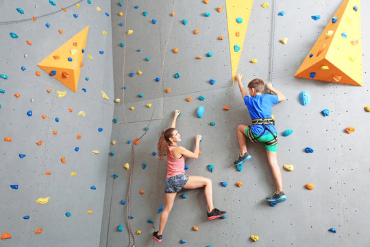 Young boy and instructor climbing wall in gym