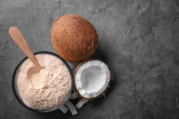 Bowl with coconut flour and fresh nuts on grey textured background