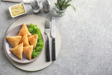 Plate with delicious baked samosas on table