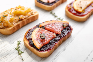 Slice of bread with jam and grapefruit on table