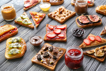 Toasts with various delicious toppings on wooden background
