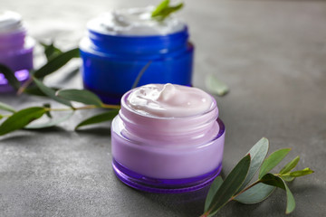 Glass jar with body cream on grey background