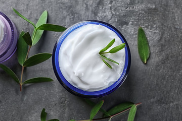 Glass jar with body cream on grey background