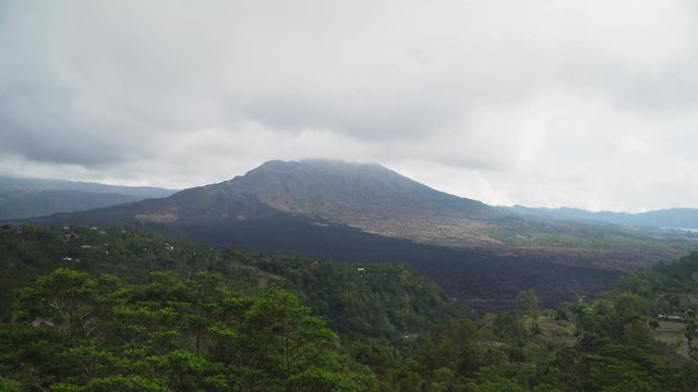 Volcano mountain covered forest, sky with clouds, traces of lava on the ground. Mount Batur Volcano in Kintamani. Mountain landscape, Bali. 4K video. Travel concept.